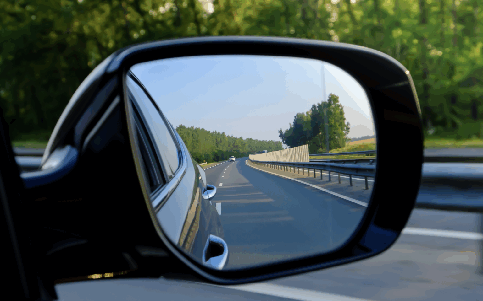 Photo of a car side mirror with a car behind in the reflection | Daniel Stark Law